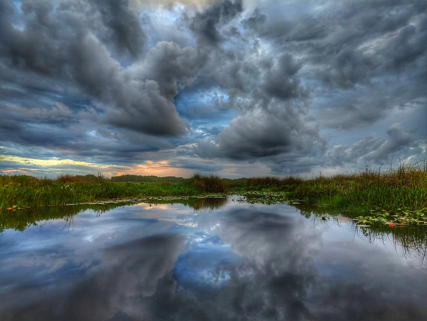 Dramatic skies reflecting in the water below creating a portal to another dimension. Photography from a boat out in the Wetlands on the Palatlakaha River.